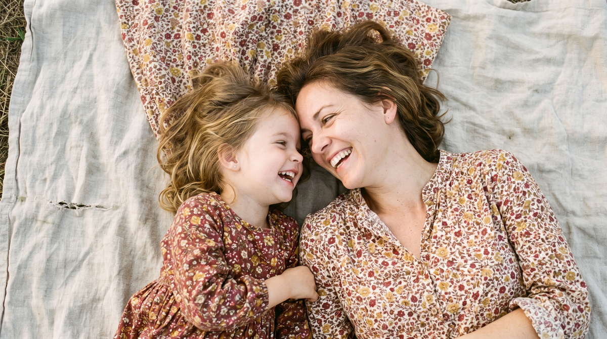 A mother and daughter lying side by side, laughing