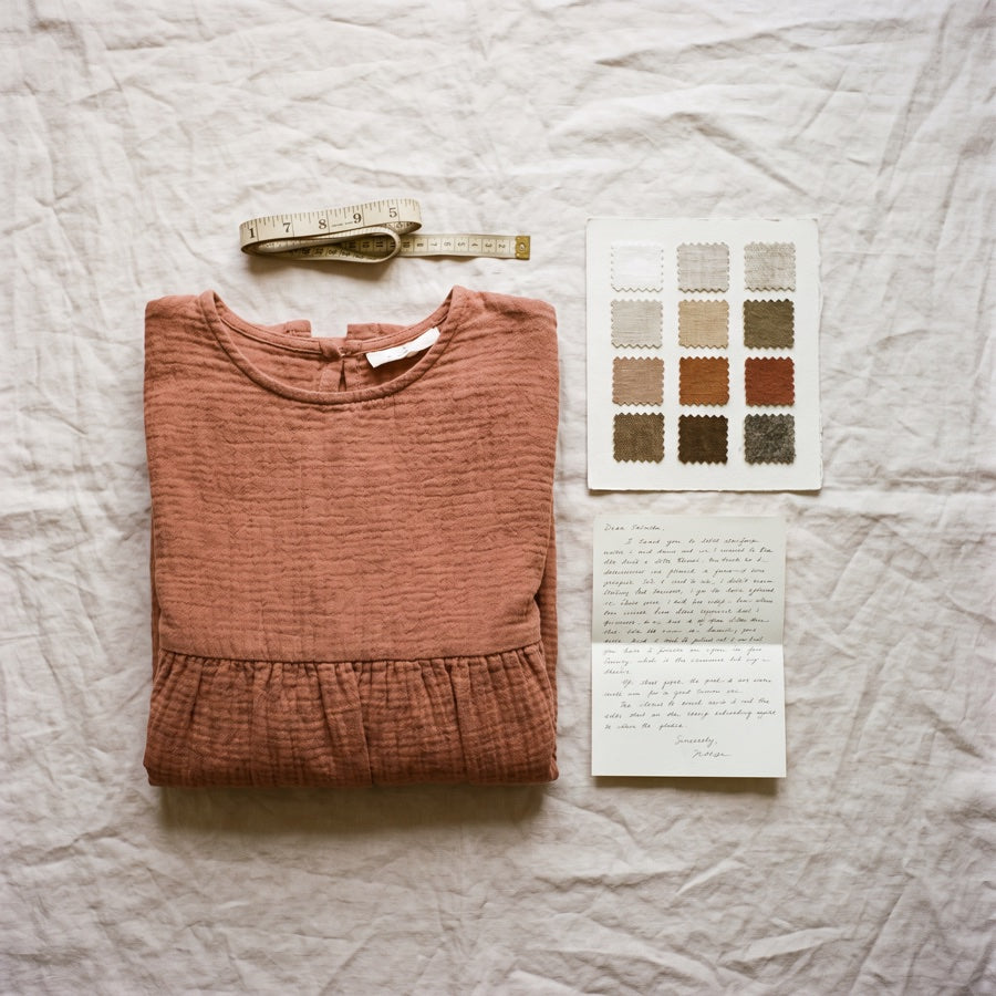 A folded cotton dress, a tape measure and a swatch card